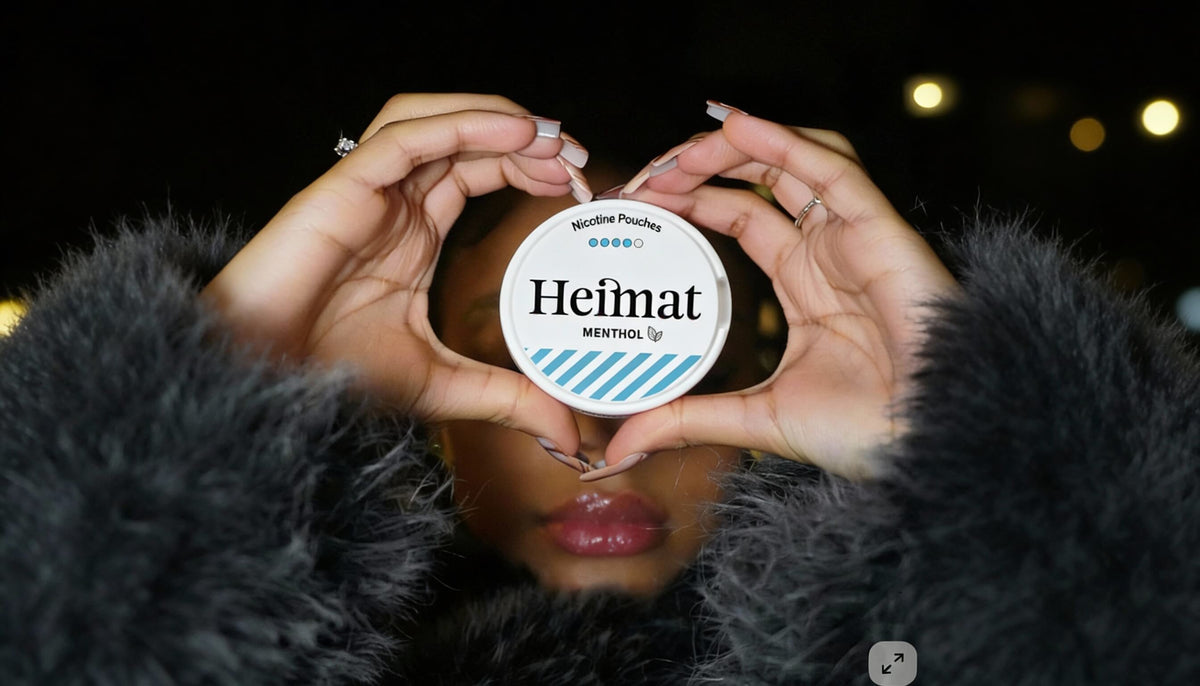 Dose de Heimat Menthol Nicotine Pouches em forma de coração sendo segurada, foto de estilo de vida com mulher em casaco preto
